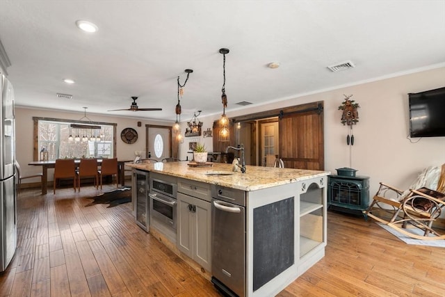 kitchen with light wood-style flooring, gray cabinetry, a sink, visible vents, and crown molding