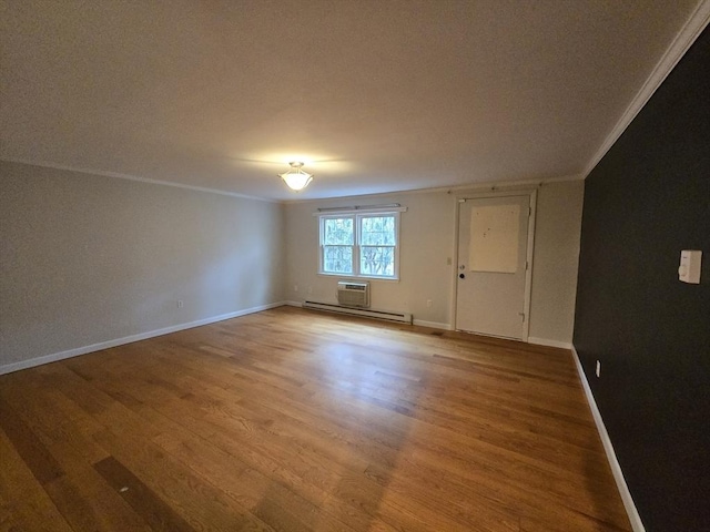 spare room with baseboard heating, crown molding, and hardwood / wood-style floors