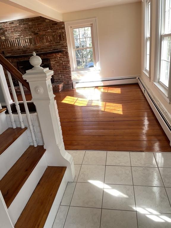 interior space featuring tile patterned flooring, baseboard heating, brick wall, and a wealth of natural light