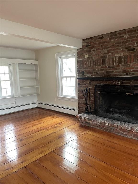 unfurnished living room featuring a brick fireplace, baseboard heating, and hardwood / wood-style floors