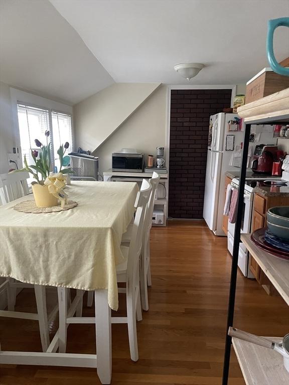 dining space with wood finished floors and vaulted ceiling