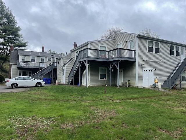 rear view of property featuring stairs, central AC unit, a lawn, and a deck