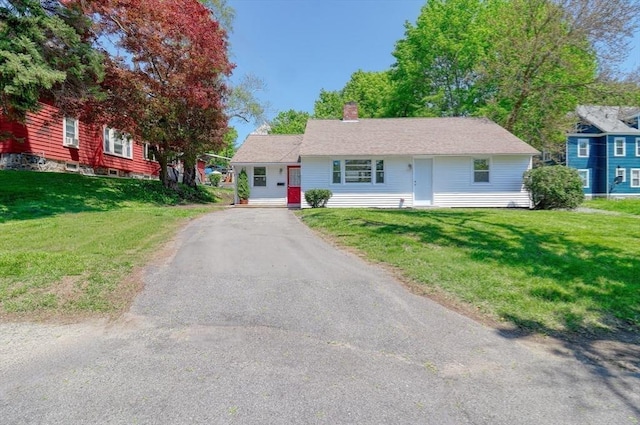 view of front of home featuring a front yard, a chimney, and driveway