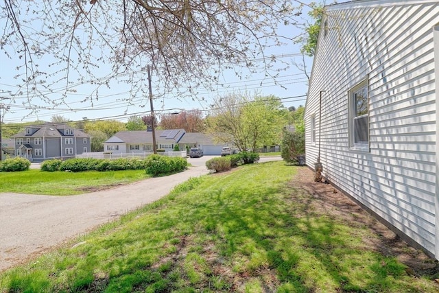 view of green lawn featuring a residential view and a detached garage