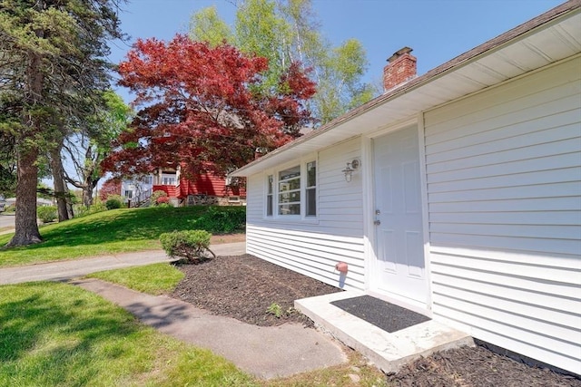 property entrance featuring a chimney and a yard