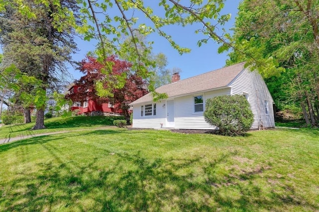rear view of house with a chimney and a lawn