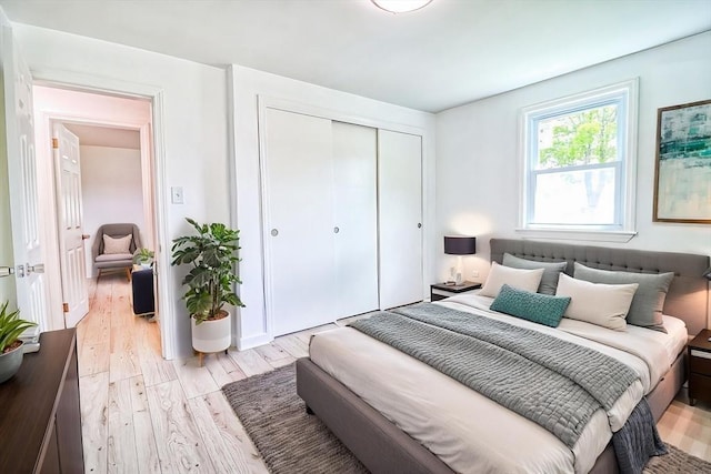 bedroom with light wood finished floors and a closet