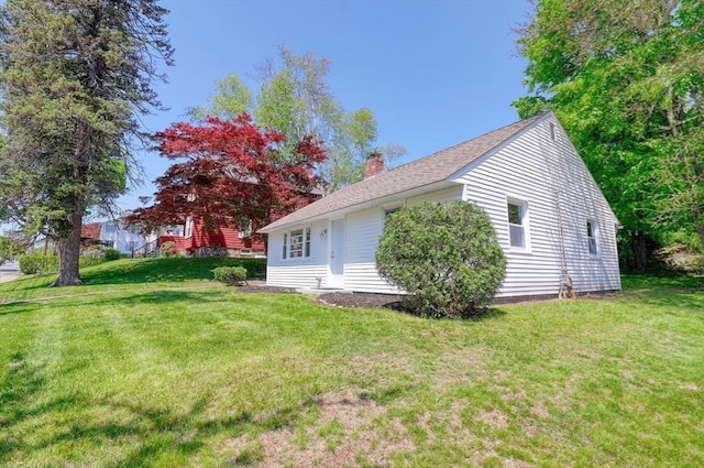 view of side of property with a chimney and a lawn