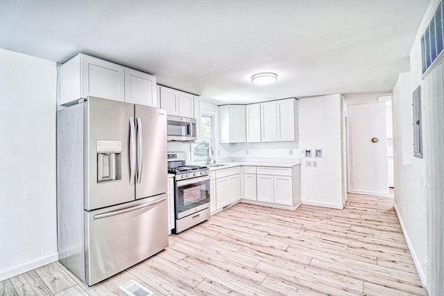 kitchen featuring stainless steel appliances, white cabinets, a sink, and baseboards