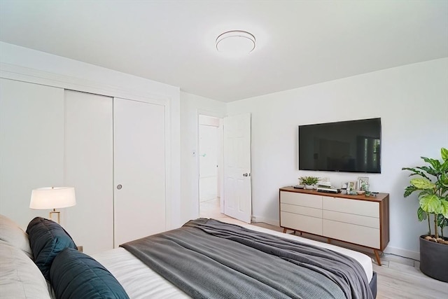 bedroom with baseboards, light wood finished floors, and a closet