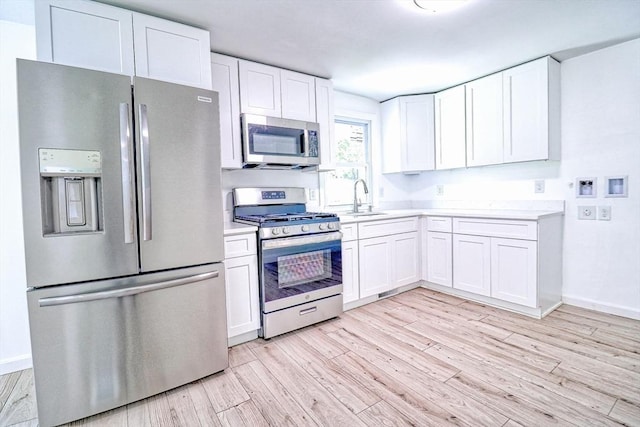 kitchen featuring appliances with stainless steel finishes, a sink, light countertops, and white cabinets