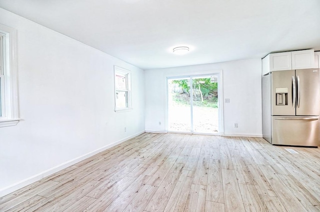 unfurnished living room with light wood-type flooring and baseboards