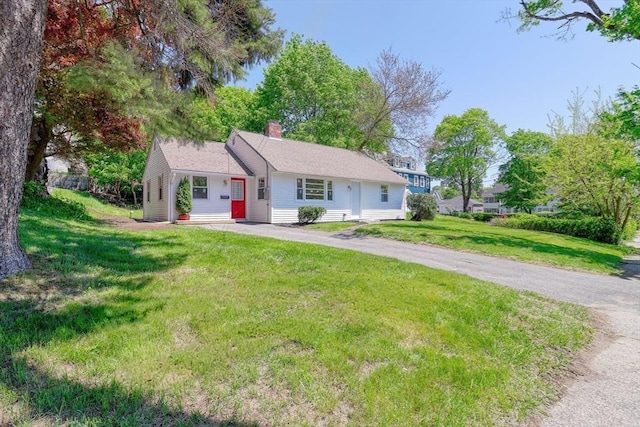view of front of house featuring a chimney, a front lawn, and asphalt driveway