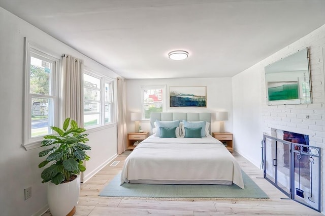 bedroom with multiple windows, wood finished floors, baseboards, and a fireplace