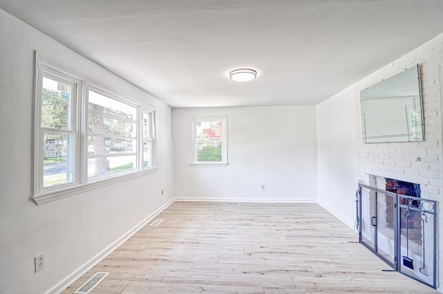 unfurnished living room featuring light wood-style floors, baseboards, and a fireplace