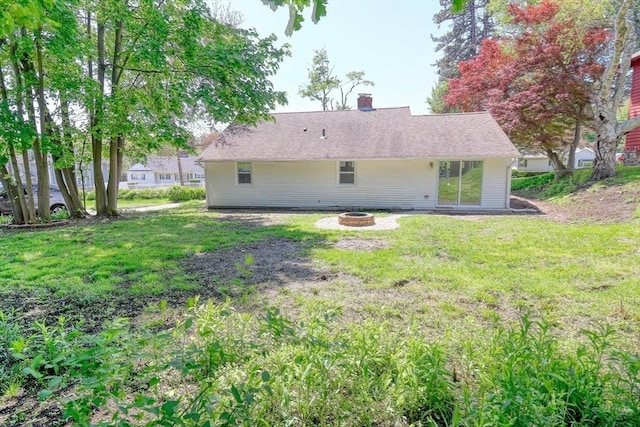 rear view of house featuring a fire pit, a lawn, and a chimney