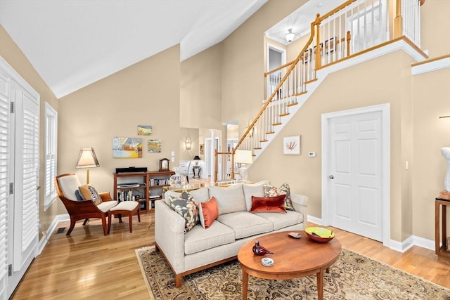 living room featuring high vaulted ceiling and light hardwood / wood-style floors