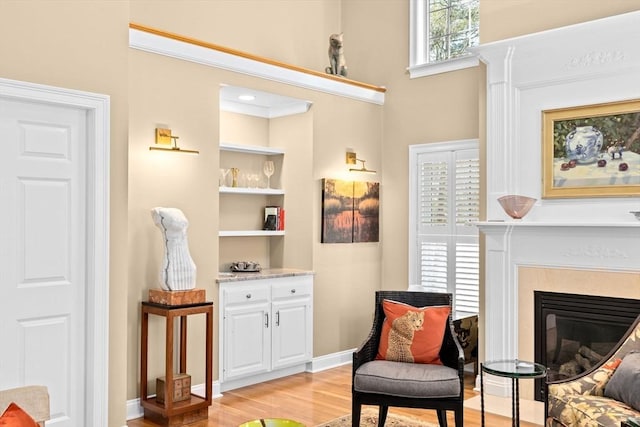 living area featuring crown molding, built in features, and light hardwood / wood-style flooring