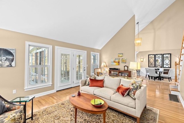 living room featuring high vaulted ceiling and light hardwood / wood-style flooring