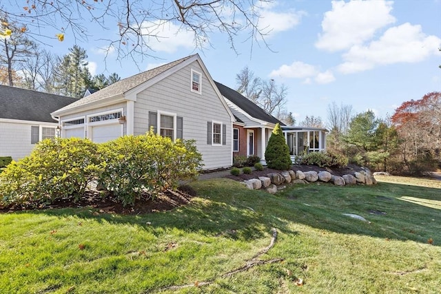 view of front of home featuring a sunroom, a front yard, and a garage