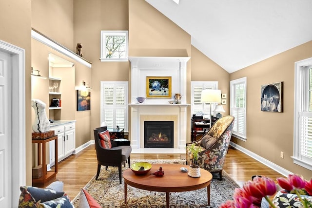 living room featuring light wood-type flooring, high vaulted ceiling, and plenty of natural light