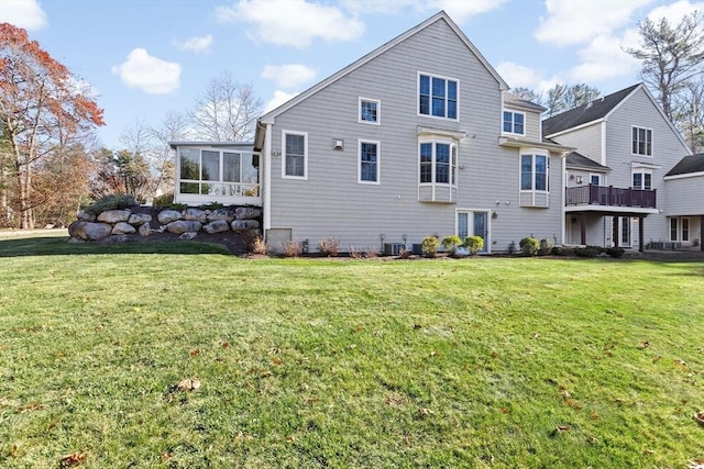 rear view of house with a yard, central air condition unit, and a sunroom