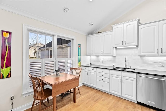 kitchen with stainless steel dishwasher, white cabinets, sink, and vaulted ceiling