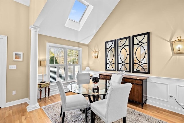 dining space with vaulted ceiling with skylight and light hardwood / wood-style floors