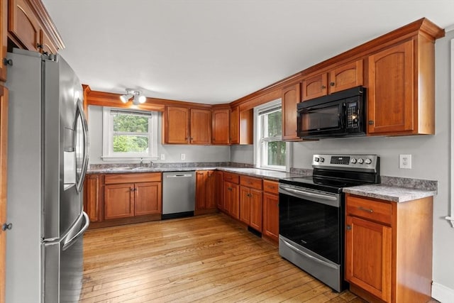 464 Ralph Talbot St, Weymouth, MA 02190 - kitchen featuring appliances with stainless steel finishes, a sink, light wood finished floors, and brown cabinets