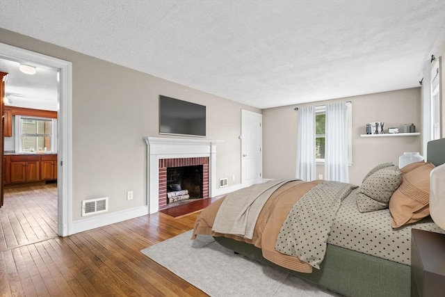 464 Ralph Talbot St, Weymouth, MA 02190 - bedroom featuring hardwood / wood-style floors, baseboards, multiple windows, a textured ceiling, and a fireplace