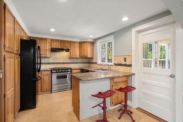 106 Nevada St, Newton, MA 02460 - kitchen with stainless steel range with gas cooktop, freestanding refrigerator, under cabinet range hood, a sink, and a peninsula