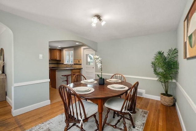 106 Nevada St, Newton, MA 02460 - dining space featuring arched walkways, light wood finished floors, and baseboards
