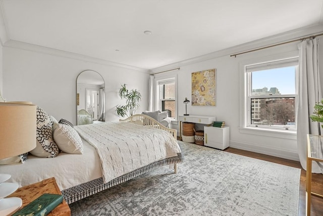 bedroom with baseboards, crown molding, and wood finished floors