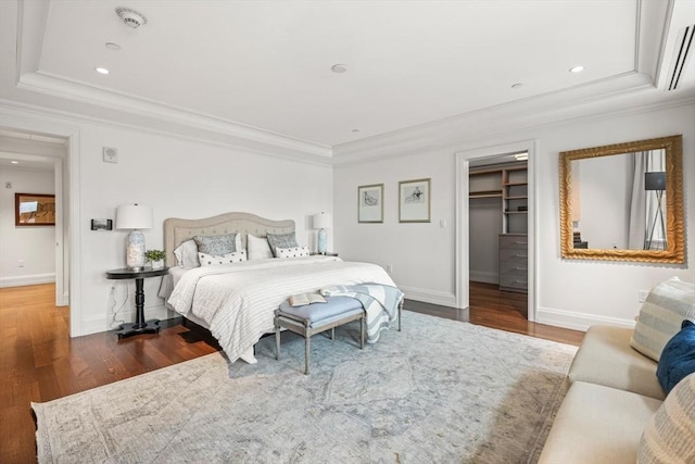 bedroom with ornamental molding, a tray ceiling, baseboards, and wood finished floors