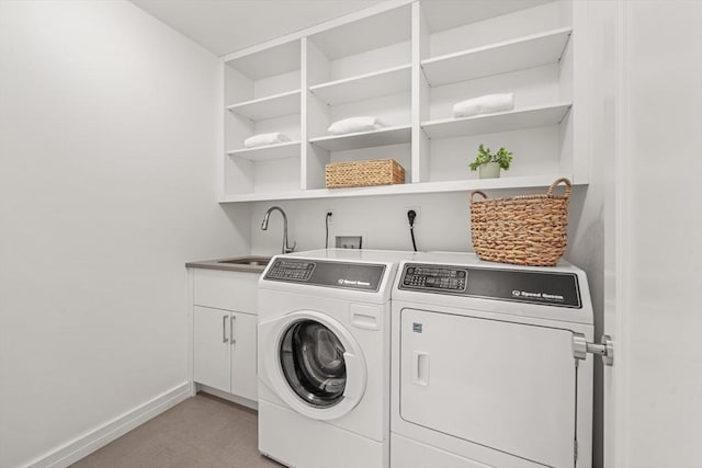 clothes washing area featuring a sink, washing machine and clothes dryer, cabinet space, and baseboards