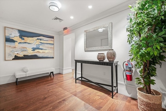 interior space featuring ornamental molding, visible vents, and wood finished floors