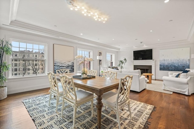 dining space featuring ornamental molding, a fireplace, baseboards, and wood finished floors