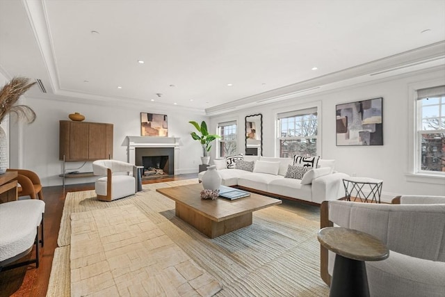 living area with ornamental molding, a fireplace with flush hearth, and a healthy amount of sunlight