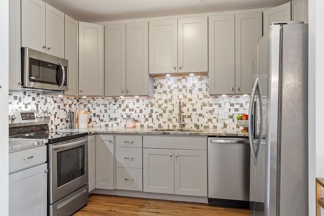 4 Harvest Dr Unit 225, North Andover, MA 01845 - kitchen featuring appliances with stainless steel finishes, light stone counters, backsplash, and light wood-style flooring