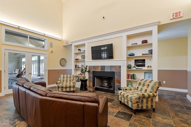 4 Harvest Dr Unit 225, North Andover, MA 01845 - living room featuring stone tile flooring, a tile fireplace, built in shelves, french doors, and a high ceiling