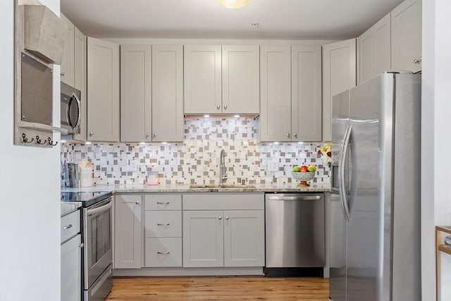 4 Harvest Dr Unit 225, North Andover, MA 01845 - kitchen featuring appliances with stainless steel finishes, light stone countertops, decorative backsplash, and light wood-type flooring