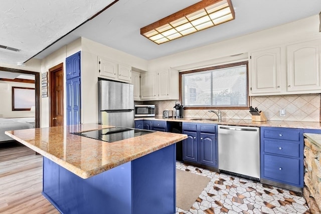 kitchen featuring appliances with stainless steel finishes, light stone countertops, white cabinets, and blue cabinetry