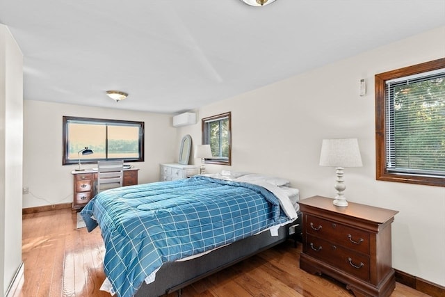 bedroom featuring wood-type flooring and a wall mounted air conditioner