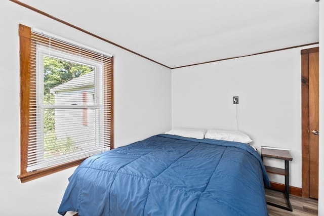 bedroom with ornamental molding, wood-type flooring, and multiple windows