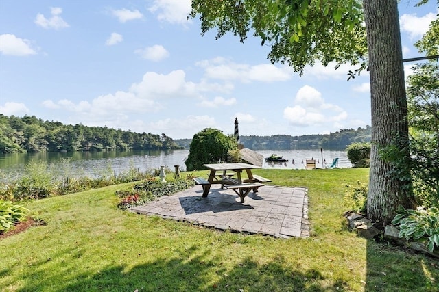 view of community featuring a water view, a yard, and a patio