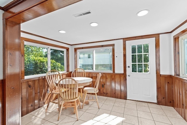 dining space featuring a healthy amount of sunlight, light tile patterned floors, and wooden walls