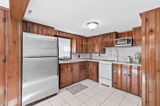 kitchen featuring light tile patterned floors, stainless steel appliances, tasteful backsplash, and sink