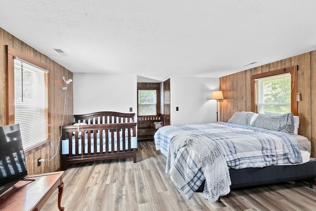 bedroom featuring multiple windows, hardwood / wood-style flooring, and wooden walls