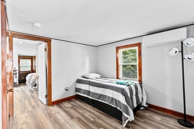 bedroom with hardwood / wood-style floors and a wall unit AC