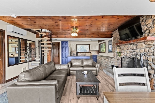 living room featuring wood ceiling, a wall unit AC, a fireplace, and light hardwood / wood-style flooring